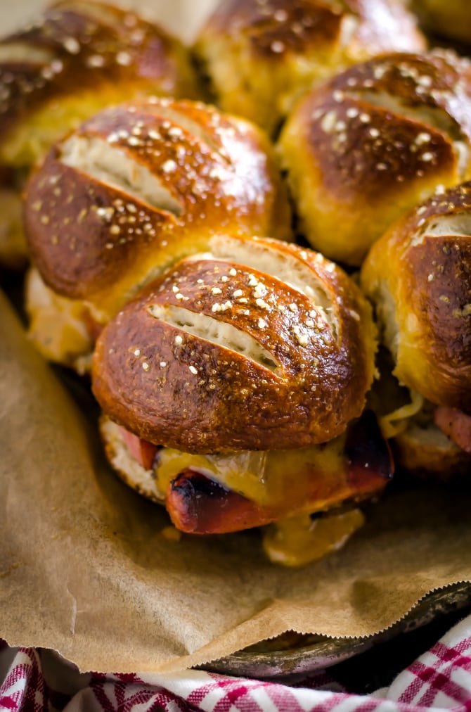 Bratwurst Sliders with Beer Cheese and Beer Braised Onions. These loaded sliders are served on pretzel buns and are perfect for parties or football season! | hostthetoast.com