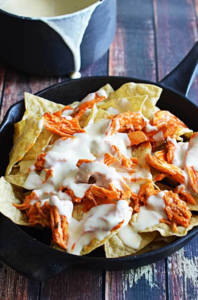 Loaded Buffalo Chicken Nachos.  Could this be any more perfect for football season?  Shredded buffalo chicken, cheesy ranch queso, blue cheese crumbles, pickled jalapenos, and chopped green onions!  The ultimate appetizer! | hostthetoast.com