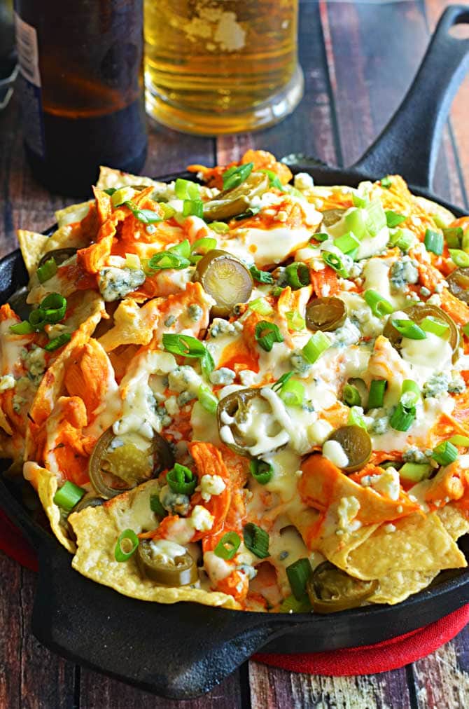 Loaded Buffalo Chicken Nachos.  Could this be any more perfect for football season?  Shredded buffalo chicken, cheesy ranch queso, blue cheese crumbles, pickled jalapenos, and chopped green onions!  The ultimate appetizer! | hostthetoast.com