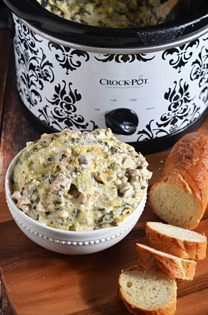 Slow Cooker Sausage, Spinach, and Artichoke Dip.  This super cheesy crock pot dip is going to be your new favorite appetizer for parties, tailgates, and more.  Best of all, it's so simple to whip together! | hostthetoast.com