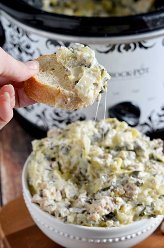 Slow Cooker Sausage, Spinach, and Artichoke Dip.  This super cheesy crock pot dip is going to be your new favorite appetizer for parties, tailgates, and more.  Best of all, it's so simple to whip together! | hostthetoast.com