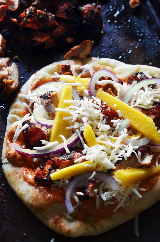 Tandoori Chicken Naan Pizzas. These grilled pizzas feature juicy tandoori chicken, mango, mozzarella, mint, cilantro, and yogurt. Premade naan make a great base for a delicious pizza dinner with Indian flair. | hostthetoast.com