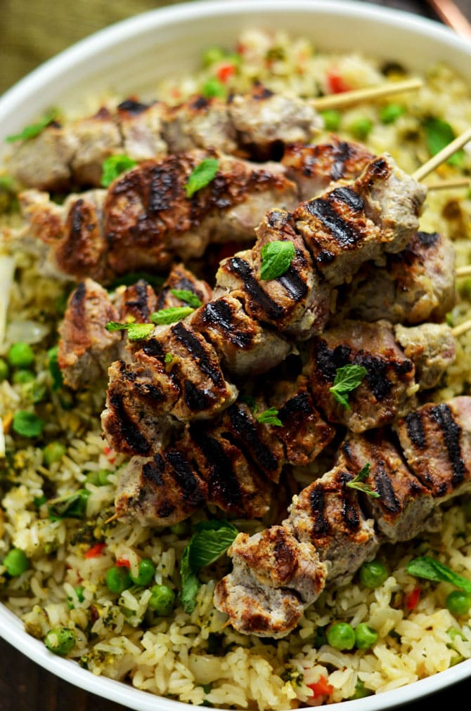 Yogurt Marinated Lamb Skewers with Mint Pistachio Pesto Pilaf. Marinating the lamb in a mixture of yogurt, garlic, lemon, and cumin makes it tender, tangy, and bright. The rice pilaf, with mint-pistachio pesto mixed in, is the perfect pairing for this springtime dinner. | hostthetoast.com