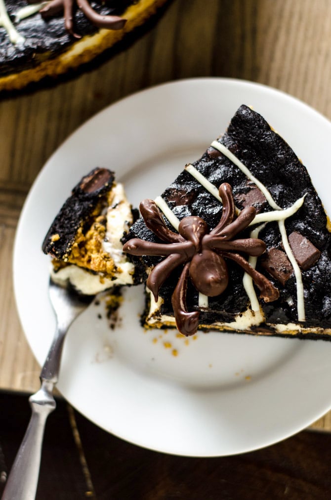 Spider Web S'more Cheesecake Brownies. This layered dessert features dark chocolate brownies, marshmallow cheesecake, and chocolate spiders. It's going to be a hit at your Halloween party! | hostthetoast.com