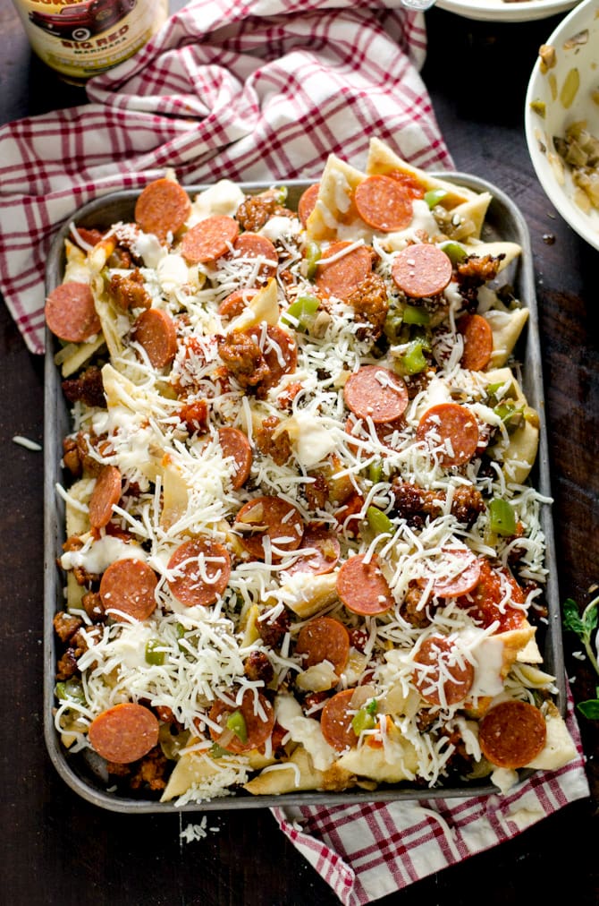 Loaded Pizza Nachos with Creamy Garlic White Sauce. All of your favorite pizza toppings on easy-to-make pizza crust chips. This is the ultimate appetizer. | hostthetoast.com