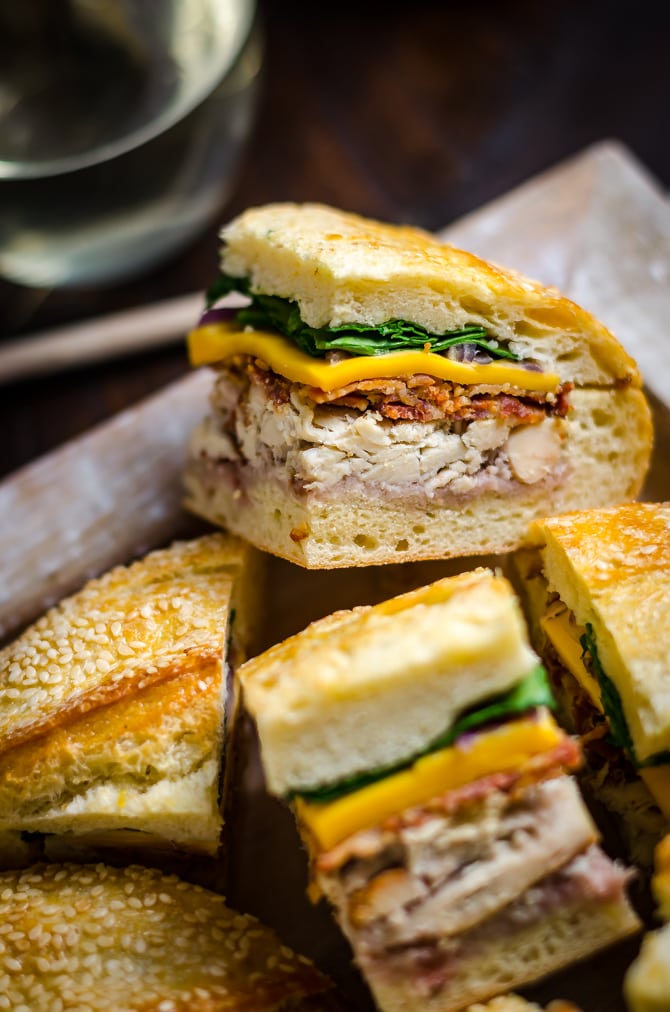 Chicken Bacon Pressed Picnic Sandwiches with Raspberry Honey Mustard. These tangy smash-hit sandwiches are great for potlucks, barbecues, picnics, parties, and all that lies in-between. With a raspberry honey mustard, chicken, bacon, cheddar cheese, red onion, and baby spinach filling, they are always devoured. Plus, you can easily make them ahead of time and transport them with no stress! | hostthetoast.com