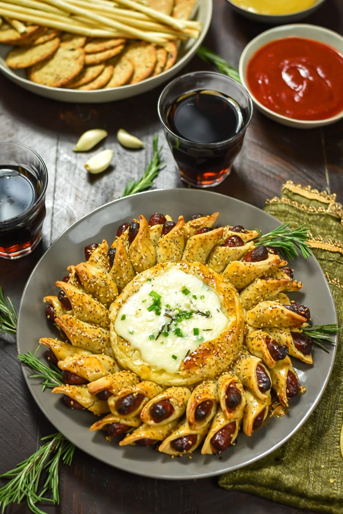 Pigs in a Blanket Baked Brie. This cheesy, garlicky, herby dip includes mini cocktail sausages in a premade pie crust! It's an easy and delicious party treat!| hostthetoast.com