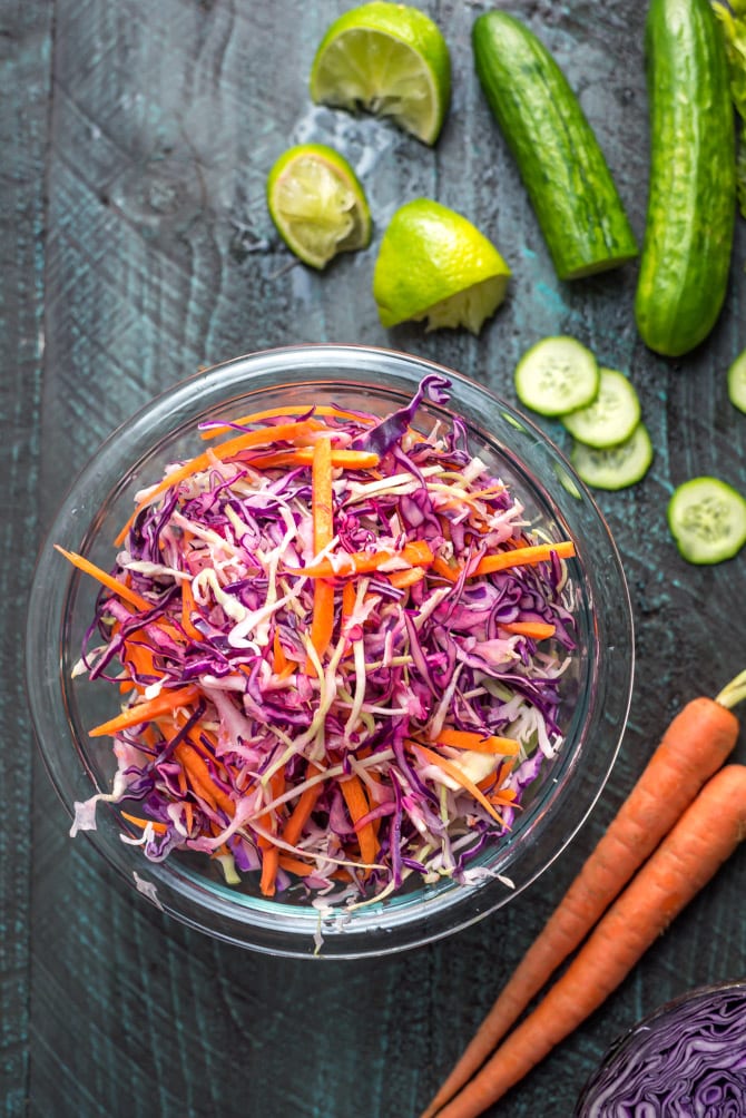 Cabbage slaw for Korean-Inspired Crispy Tofu Tacos in a glass bowl on a blue wood table.