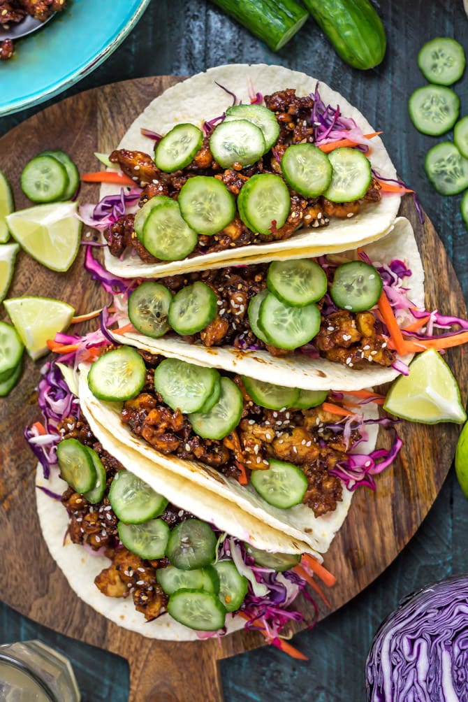 Korean-Inspired Crispy Tofu Tacos on a wooden cutting board surrounded by lime wedges.