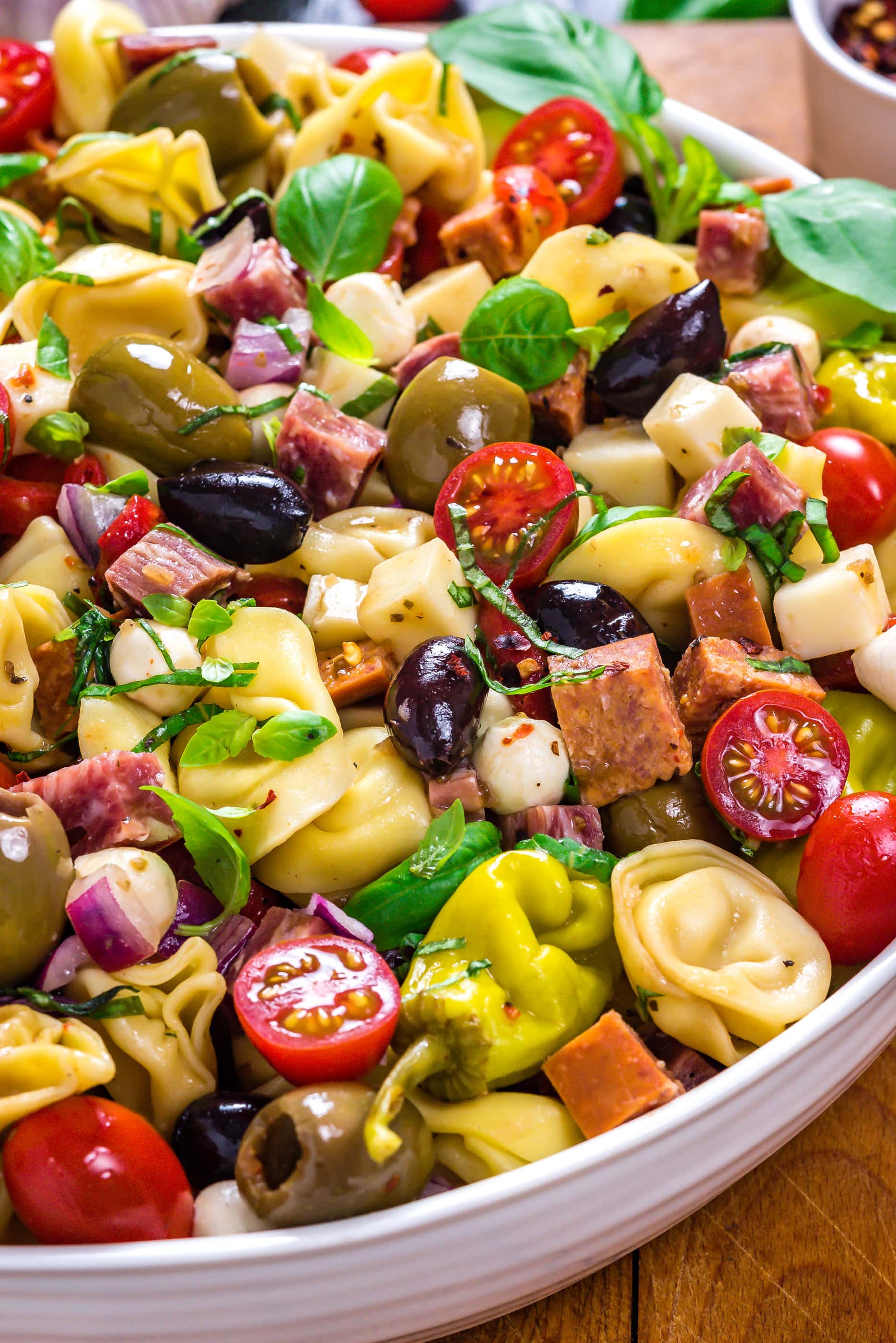 A close up side view of Antipasto Tortellini Pasta Salad in a large white bowl.