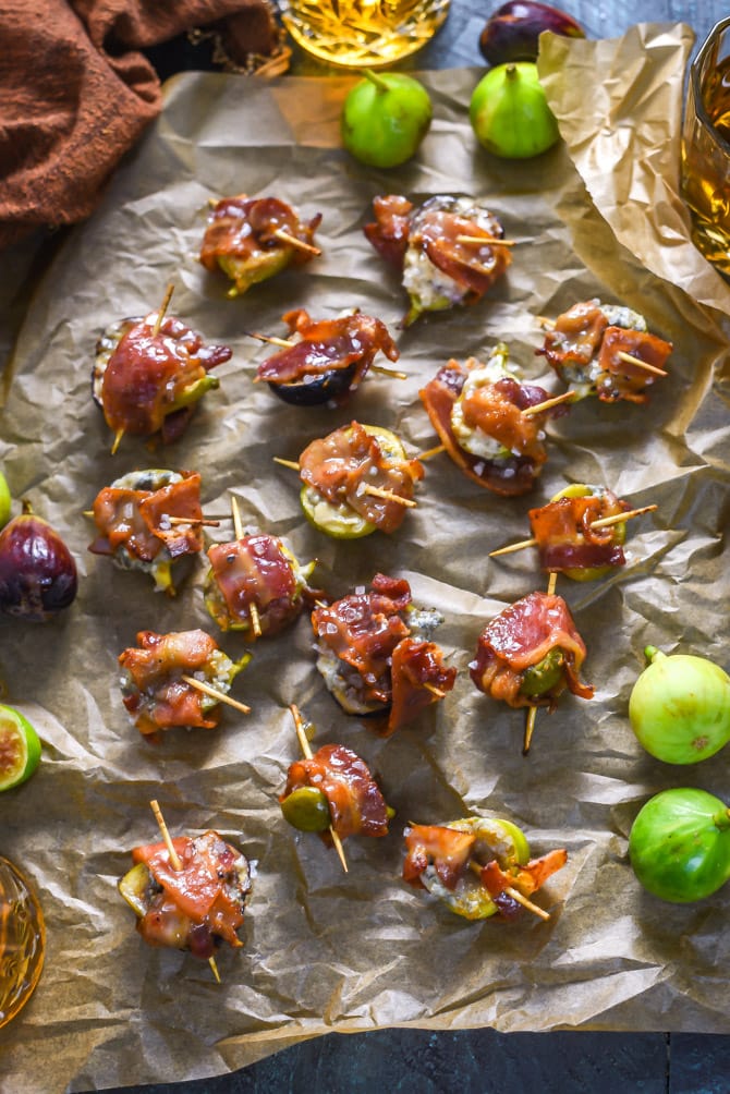 An overhead shot of Bacon-Wrapped Figs with Blue Cheese and Bourbon Caramel on a crumpled sheet of parchment paper.
