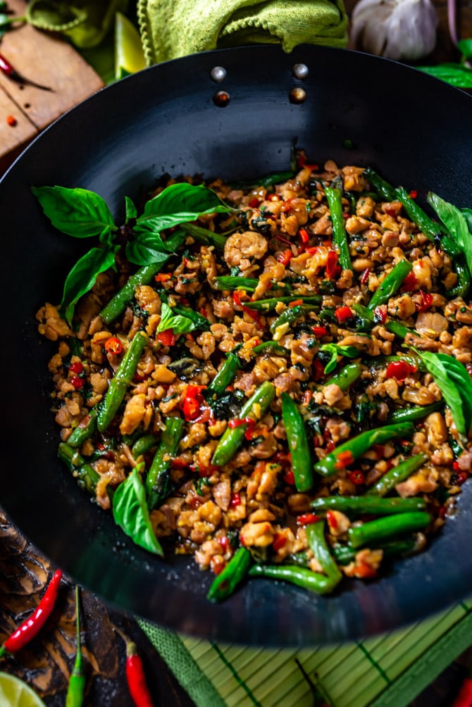 A close up view of Thai Basil Chicken Stir Fry in the wok with thai basil to garnish.