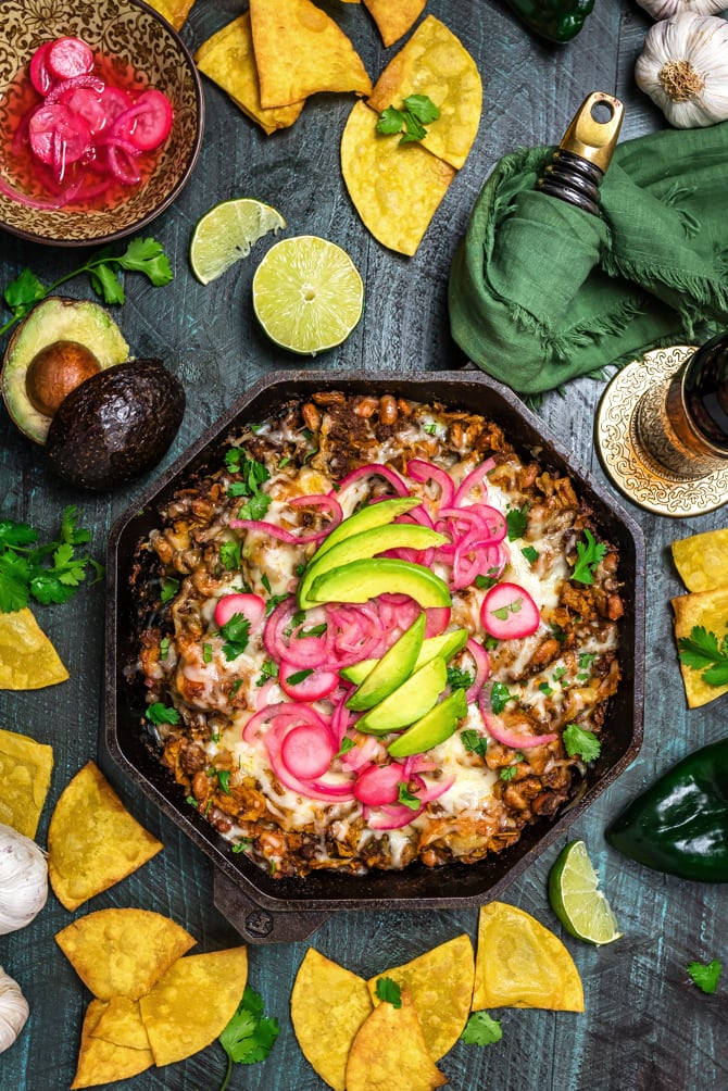 This Easy Enchilada Skillet is a one-pot meal that features from-scratch flavors. (Yup, there's no canned enchilada sauce in this one)! Loaded up with ground beef, beans, and corn tortilla strips; smothered in sauce and cheese; broiled until melty; and topped with tangy pickled onions and radishes, this dinner recipe has it all. | hostthetoast.com