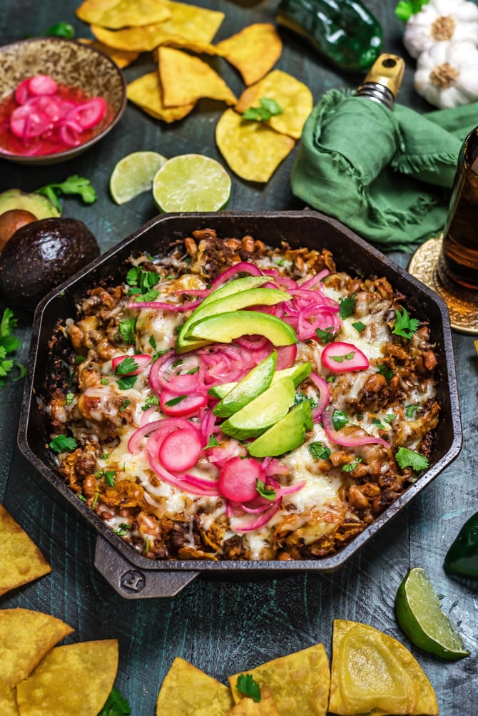 This Easy Enchilada Skillet is a one-pot meal that features from-scratch flavors. (Yup, there's no canned enchilada sauce in this one)! Loaded up with ground beef, beans, and corn tortilla strips; smothered in sauce and cheese; broiled until melty; and topped with tangy pickled onions and radishes, this dinner recipe has it all. | hostthetoast.com