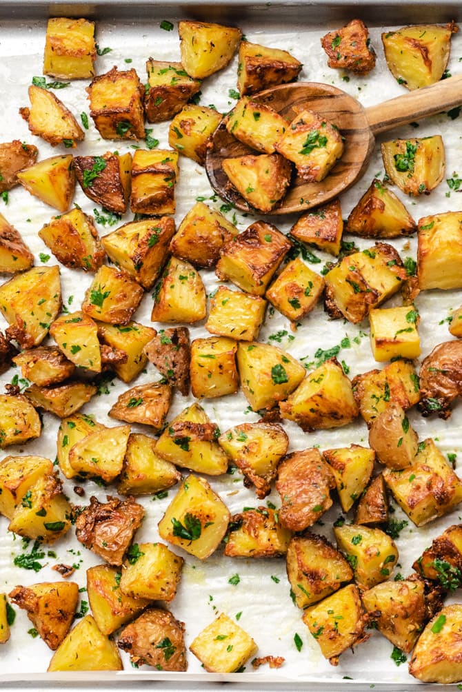 These easy-to-make Oven Roasted Red Potatoes are tossed with garlic, herbs, and parmesan cheese, and then baked until beautifully golden and crisp. Serve them as-is. or finish with butter and extra fresh parsley for a truly decadent and drooled-over side dish. 