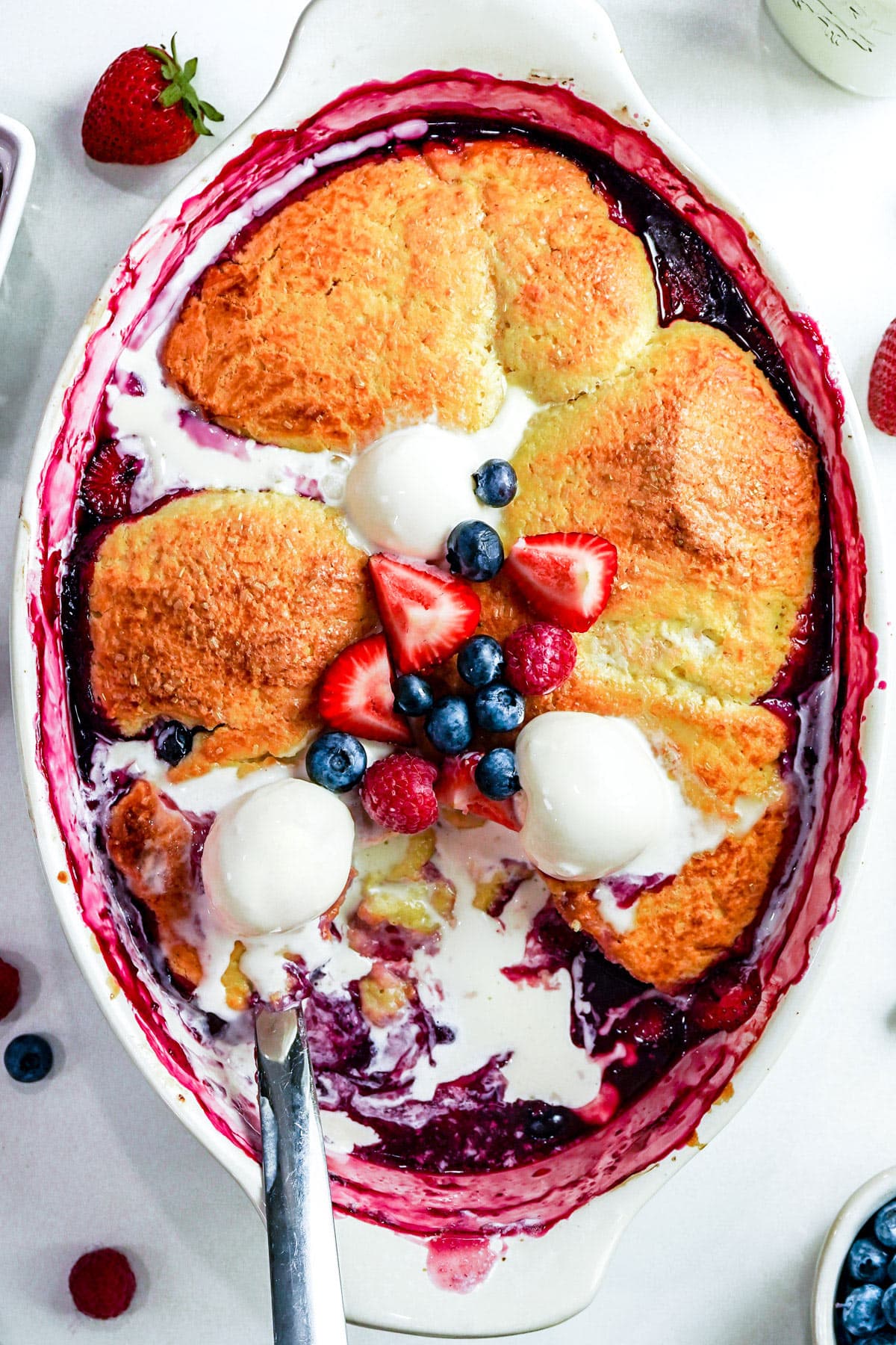 Berry cobbler with vanilla ice cream and fresh berries on a white background