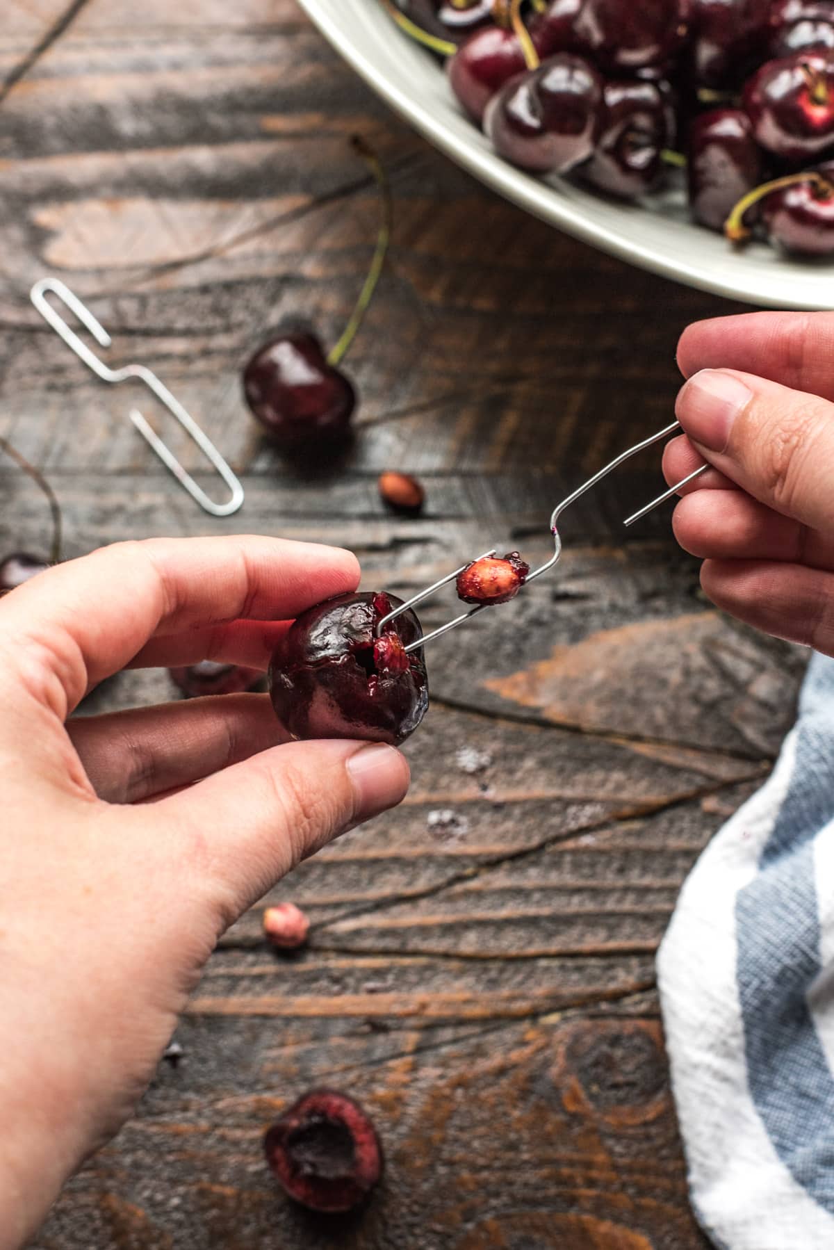 An S-shaped paperclip inserted into a cherry and displaying a removed pit.