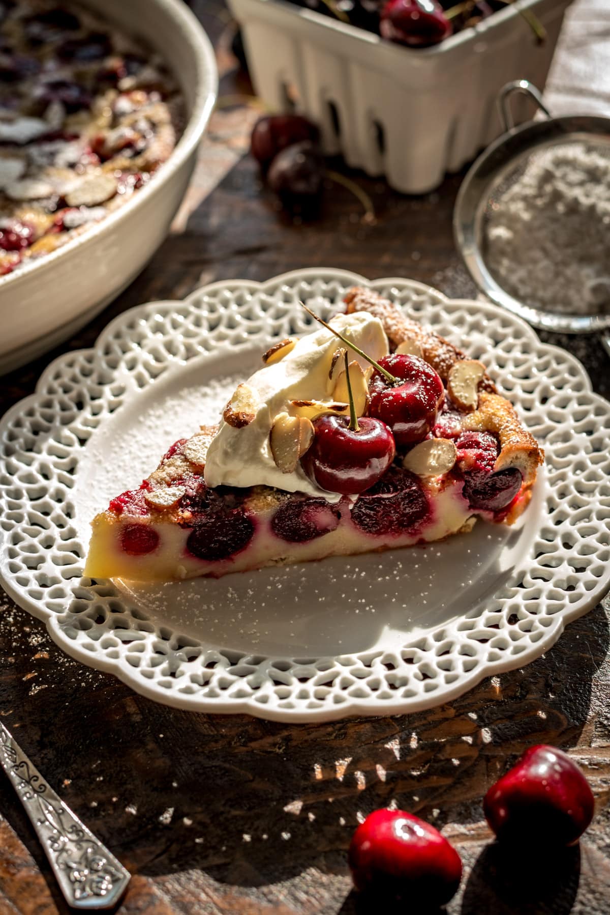 A sideview of a slice of cherry clafoutis showing the cherries encased in the baked custard.