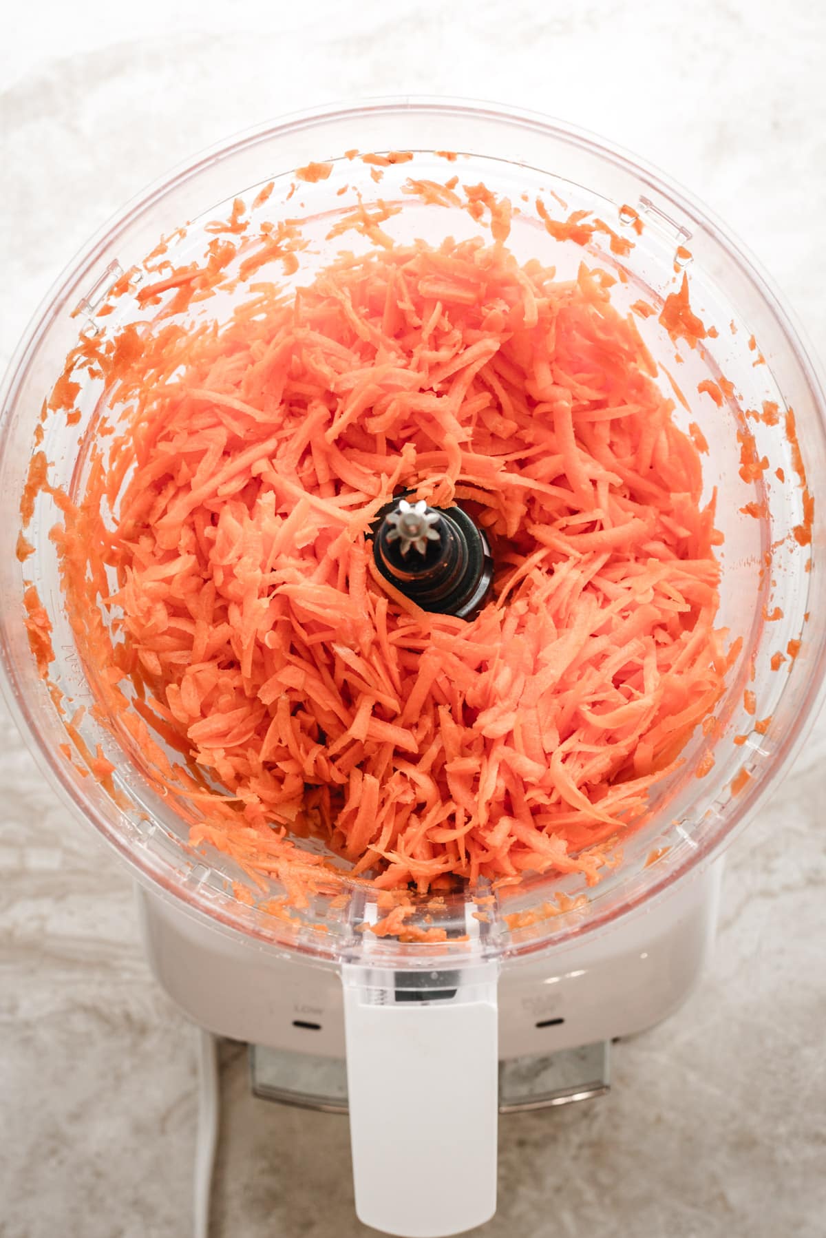 Shredded carrots in a food processor for carrot cake cupcakes